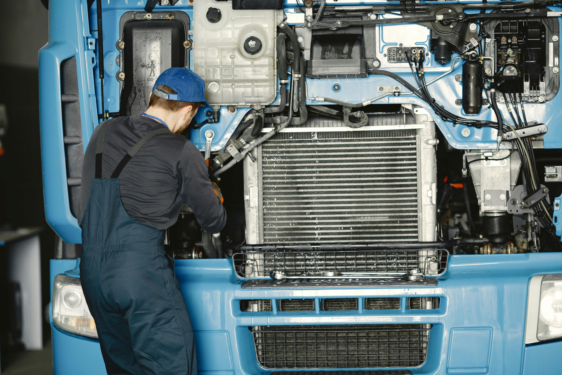 Professional diesel mechanic working on heavy-duty blue truck